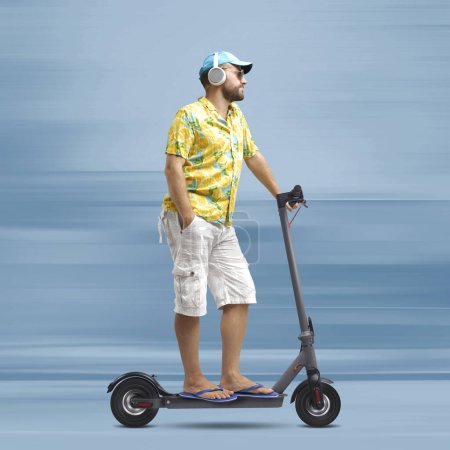 Foto de Cool hombre elegante con una camisa de playa de colores y montar un scooter eléctrico ecológico rápido, concepto de movilidad inteligente - Imagen libre de derechos