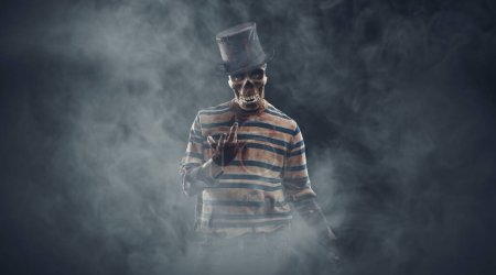Téléchargez les photos : Personnage maléfique effrayant avec tête de crâne et vêtements sanglants déchiré regardant la caméra, concept d'Halloween et d'horreur, espace de copie - en image libre de droit