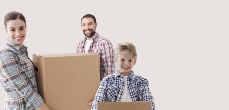 Photo for Young family moving into a new house, they are carrying full cardboard boxes, the boy is helping - Royalty Free Image