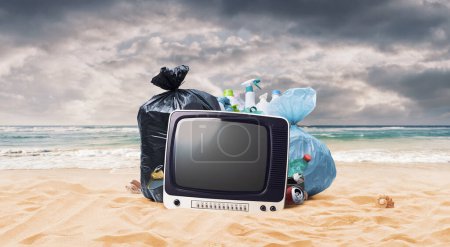 Téléchargez les photos : Assortiment de déchets abandonnés et vieux téléviseur sur la plage, concept de protection de l'environnement et de contamination - en image libre de droit
