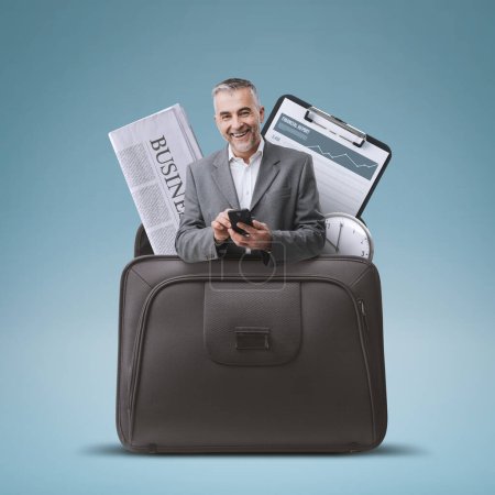 Foto de Empresario que utiliza un teléfono inteligente y artículos de oficina en un maletín, concepto de soluciones comerciales - Imagen libre de derechos