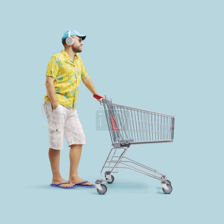 Foto de Cool chico haciendo compras de comestibles, él está empujando un carrito de compras de supermercado - Imagen libre de derechos