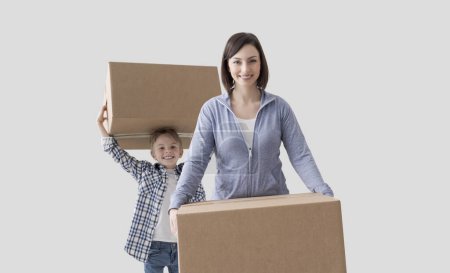 Photo for Young mother and child carrying boxes, they are moving into their new home - Royalty Free Image