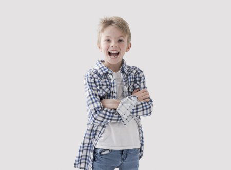 Foto de Lindo niño rubio feliz posando con los brazos cruzados y sonriente, fondo blanco - Imagen libre de derechos