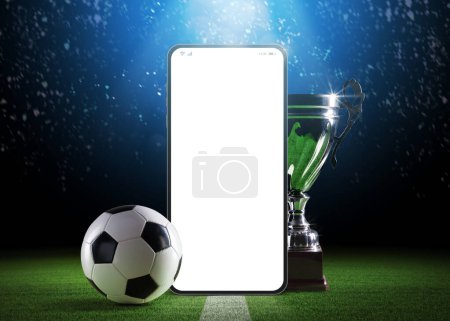 Foto de Teléfono inteligente en blanco, copa y pelota de fútbol en el campo del estadio: campeonato de fútbol y aplicación de apuestas deportivas - Imagen libre de derechos
