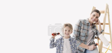 Téléchargez les photos : Joyeux jeune femme et enfant tenant un rouleau de peinture, ils peignent et décorent leur maison, bannière avec espace de copie - en image libre de droit