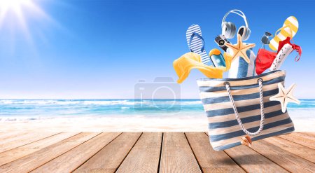 Téléchargez les photos : Sac de plage volant, accessoires colorés tombant et plage de sable en arrière-plan : concept de vacances d'été - en image libre de droit