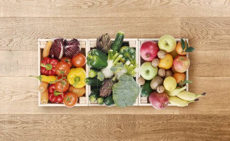 Foto de Frutas y verduras frescas y sabrosas en cajas de madera sobre una mesa de madera, concepto de comida saludable - Imagen libre de derechos