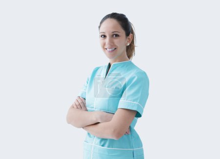 Foto de Joven enfermera profesional posando con los brazos cruzados y sonriendo a la cámara - Imagen libre de derechos