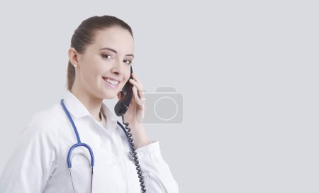 Photo for Smiling female doctor having a phone call, she is giving advice to a patient, healthcare and assistance concept - Royalty Free Image
