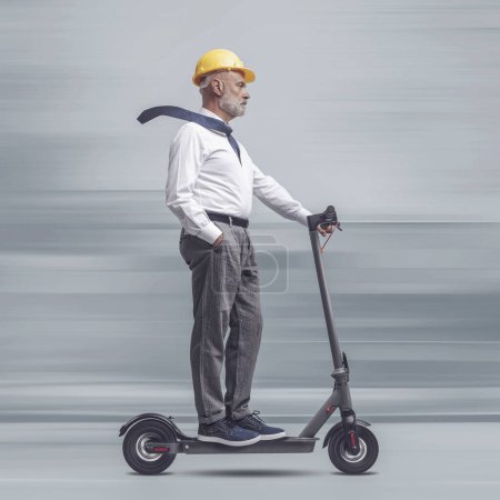 Foto de Ingeniero senior profesional que usa casco de seguridad y monta un scooter eléctrico, ingeniería y concepto de tecnología - Imagen libre de derechos