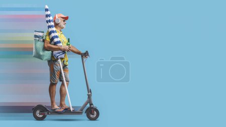 Téléchargez les photos : Drôle heureux touriste senior aller à la plage, il tient un parasol et monter un scooter électrique rapide - en image libre de droit