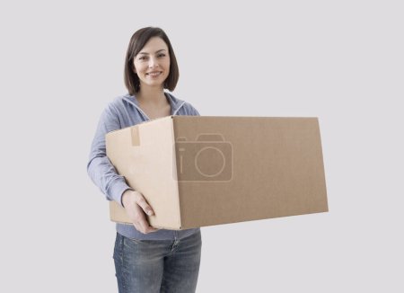 Foto de Mujer feliz sosteniendo una gran caja de cartón, se está mudando a su nuevo hogar - Imagen libre de derechos