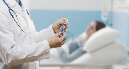 Téléchargez les photos : Médecin professionnel tenant un thermomètre, il prend la température d'un patient à l'hôpital - en image libre de droit