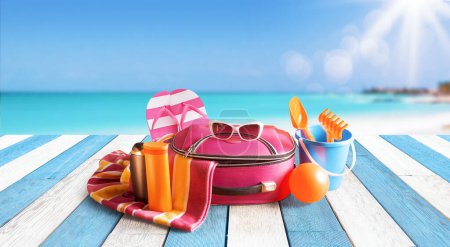 Photo for Travel bag, colorful accessories on the beach deck and sea in the background: summer vacations and travel concept - Royalty Free Image