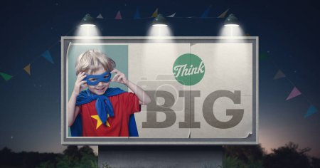 Photo for Large billboard advertisement with cute superhero kid and motivational quote: think big - Royalty Free Image
