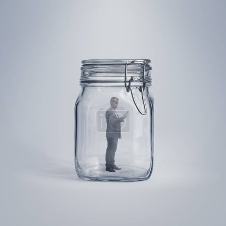 Téléchargez les photos : Homme d'affaires d'entreprise piégé dans un bocal en verre, il utilise un smartphone - en image libre de droit