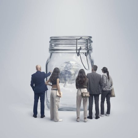 Foto de Grupo de diversas personas mirando al planeta Tierra dentro de un frasco, concepto de conservación ambiental y cooperación - Imagen libre de derechos