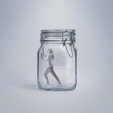 Mujer joven asustada atrapada en un enorme frasco de vidrio, está desesperada e incapaz de escapar