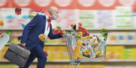 Téléchargez les photos : Homme d'affaires rapide courir et pousser un panier de supermarché - en image libre de droit