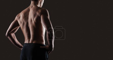 Foto de Atractivo hombre sensual posando y mostrando su espalda muscular, fitness y concepto de entrenamiento, espacio de copia - Imagen libre de derechos