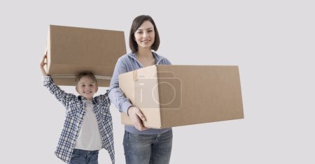Photo for Young mother and child carrying boxes, they are moving into their new home - Royalty Free Image