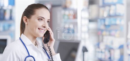 Foto de Farmacéutica profesional que trabaja en la farmacia, está recibiendo una llamada telefónica y dando consejos - Imagen libre de derechos