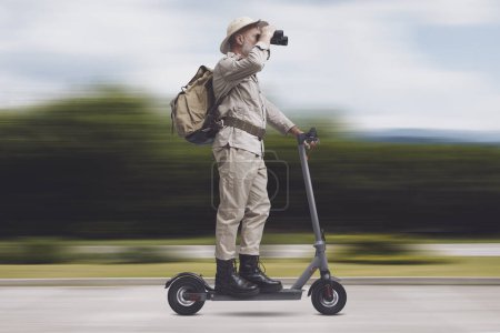 Téléchargez les photos : Explorateur senior drôle chevauchant un e-scooter, Voyage durable et concept d'aventure - en image libre de droit