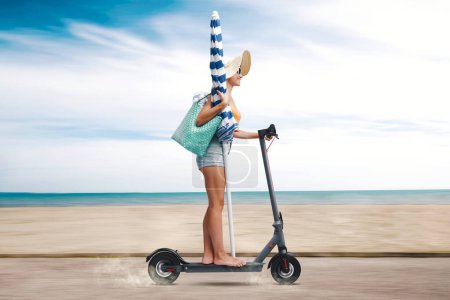 Téléchargez les photos : Femme heureuse en vacances, elle roule sur un scooter électrique et va à la plage - en image libre de droit
