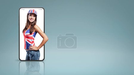 Téléchargez les photos : Sourire fille britannique regardant la caméra dans un vidéocall smartphone et souriant, concept en ligne - en image libre de droit