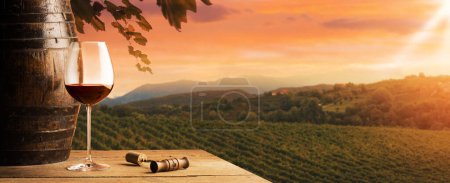 Téléchargez les photos : Verre de vin rouge et tonneau avec vue sur les vignobles en arrière-plan, arrière-plan viticole - en image libre de droit