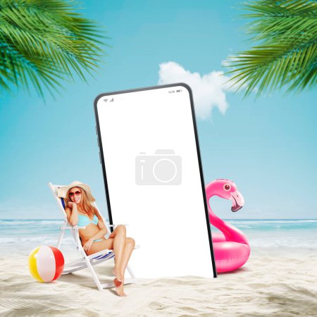 Foto de Joven hermosa mujer relajante en la playa y gran teléfono inteligente con pantalla en blanco - Imagen libre de derechos