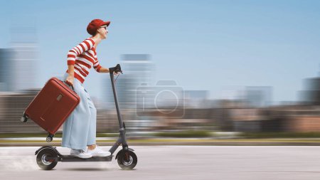 Téléchargez les photos : Femme touristique à la mode voyageant avec un scooter électrique, concept de mobilité durable - en image libre de droit