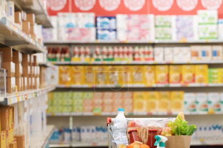 Téléchargez les photos : Supermarché intérieur allée avec panier complet, épicerie et concept de commerce - en image libre de droit
