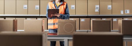 Photo for Young female worker checking packages and orders in the warehouse - Royalty Free Image