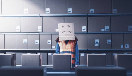 Ouvrière d'entrepôt déprimée frustrée avec une boîte sur la tête : aliénation dans le concept de lieu de travail