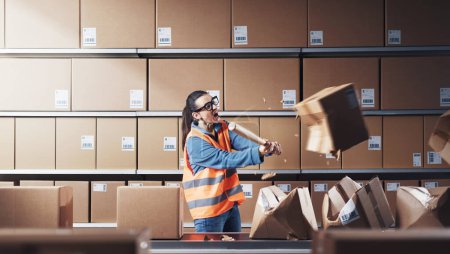 Photo for Aggressive rebellious warehouse worker smashing boxes at work, she is frustrated and angry - Royalty Free Image
