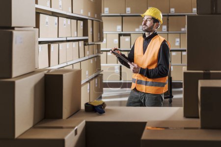 Photo for Warehouse worker holding a clipboard and checking packages, logistics and shipment concept - Royalty Free Image