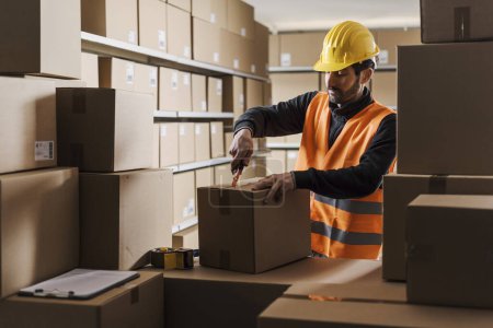 Photo for Warehouse worker opening a cardboard box using a cutter - Royalty Free Image
