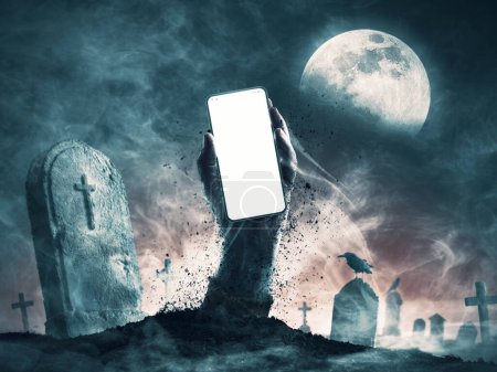 Téléchargez les photos : Main de zombie effrayant sortir d'une tombe et tenant un smartphone avec écran vide, copier l'espace - en image libre de droit