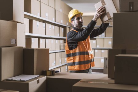 Empleado de almacén apilando cajas de cartón y comprobando pedidos: logística y concepto de entrega