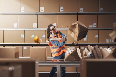 Aggressive rebellious warehouse worker smashing boxes at work, she is frustrated and angry