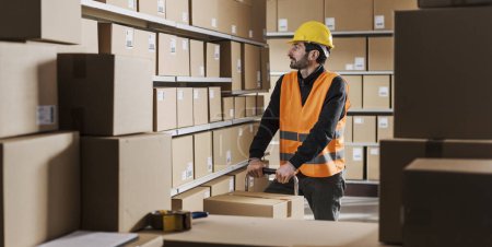 Téléchargez les photos : Employé de l'entrepôt au travail, il prépare les livraisons et déplace les boîtes dans l'entrepôt - en image libre de droit