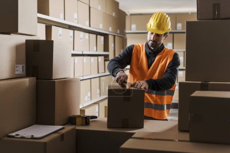 Téléchargez les photos : Ouvrier de l'entrepôt ouvrant une boîte en carton à l'aide d'un cutter - en image libre de droit