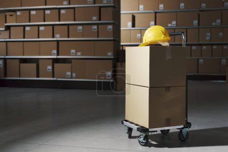 Photo for Distribution warehouse interior with delivery boxes and trolley: logistics, delivery and storage concept - Royalty Free Image