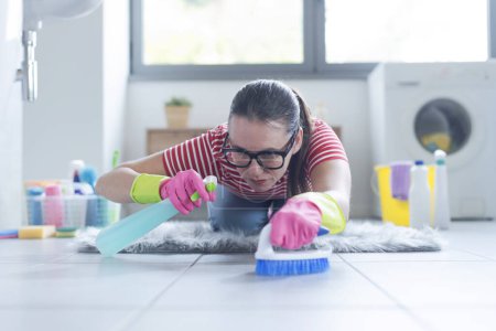 Foto de Mujer obsesionada con la higiene, está limpiando el piso del baño con un detergente - Imagen libre de derechos