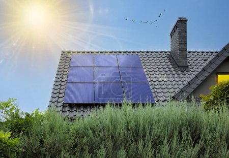 Foto de Hermosa casa moderna con paneles solares. Cielo despejado, sol. Casa con fotovoltaica en el techo y rayos de sol. - Imagen libre de derechos