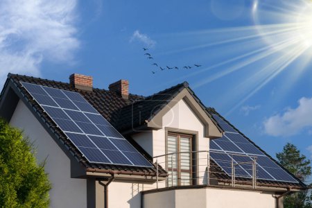 Téléchargez les photos : Panneaux photovoltaïques sur le toit. Maison moderne et énergie solaire. Rayons de soleil et de verdure. Le concept d'un environnement durable, la construction. - en image libre de droit