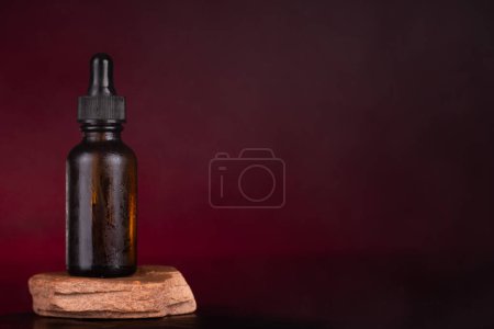 Amber Dropper Bottle on Natural Stone Pedestal with Elegant Maroon Backdrop