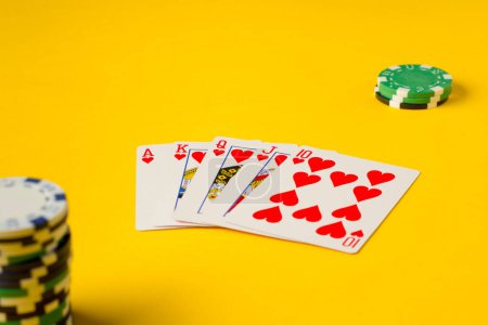 Foto de Escalera Real. Cinco cartas de juego la mano escalera real de póquer. Fichas de poker en amarillo. éxito en el juego - Imagen libre de derechos